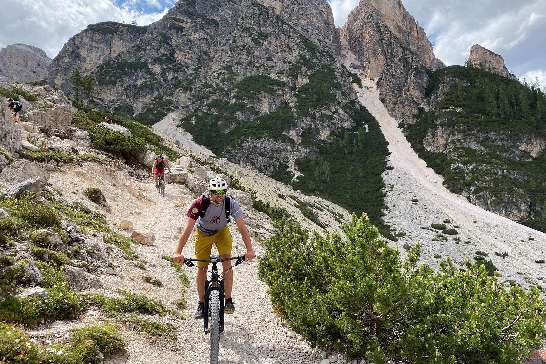 Due ciclisti pedalano in mountain bike su un sentiero roccioso con alte e aspre montagne sullo sfondo. - Hotel Innerhofer