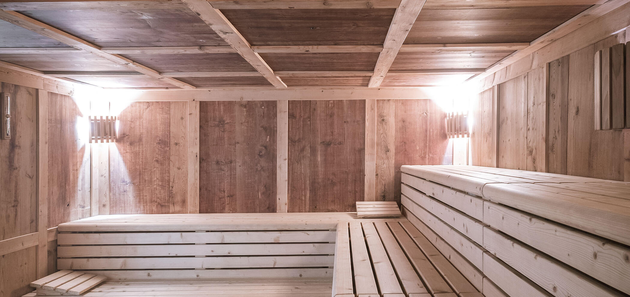 Sala sauna vuota in legno con panche a gradoni e illuminazione soffusa a parete. - Hotel Innerhofer