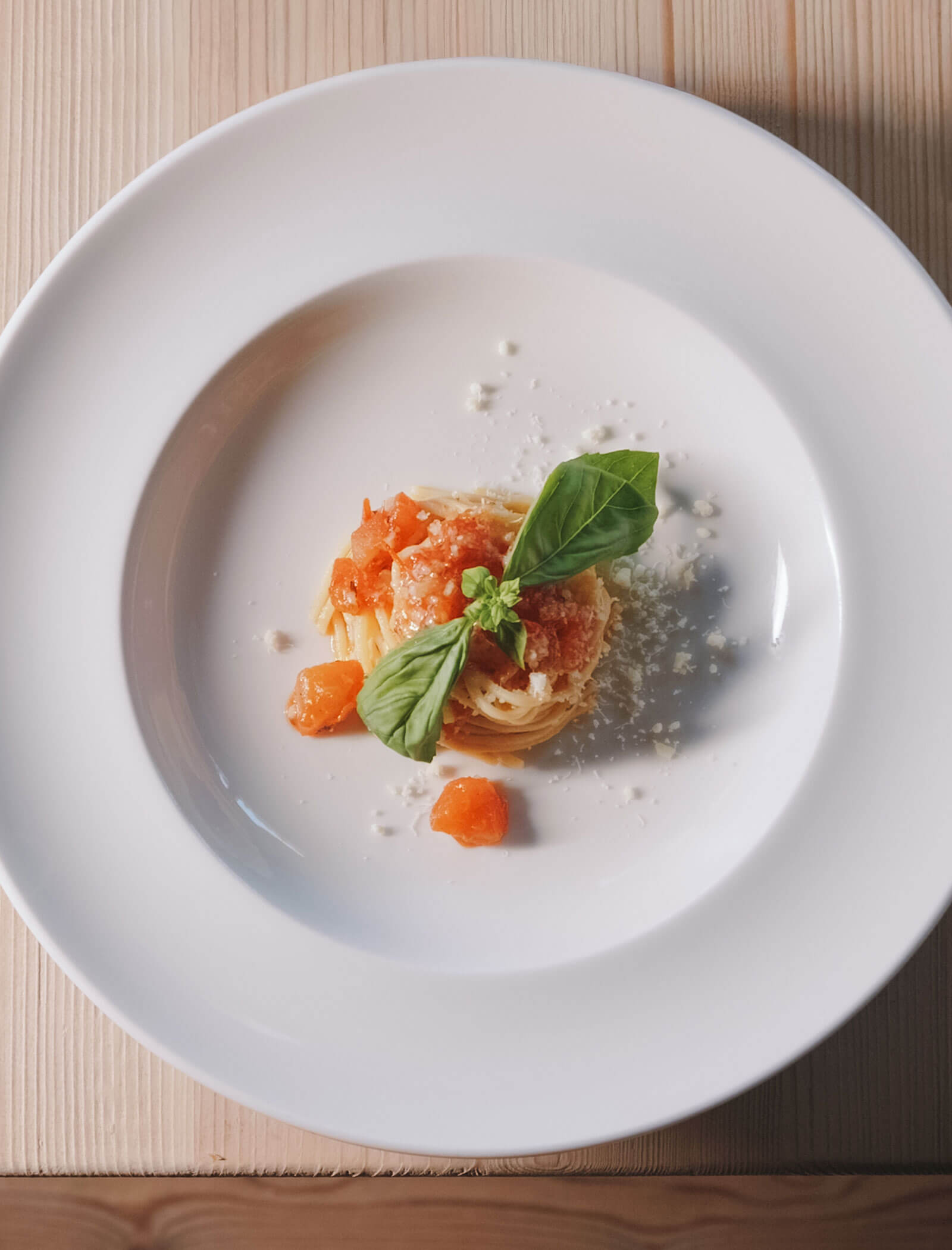 Eine kleine Portion Spaghetti mit Tomatensauce, geriebenem Käse und Basilikum auf einem weißen Teller. - Hotel Innerhofer