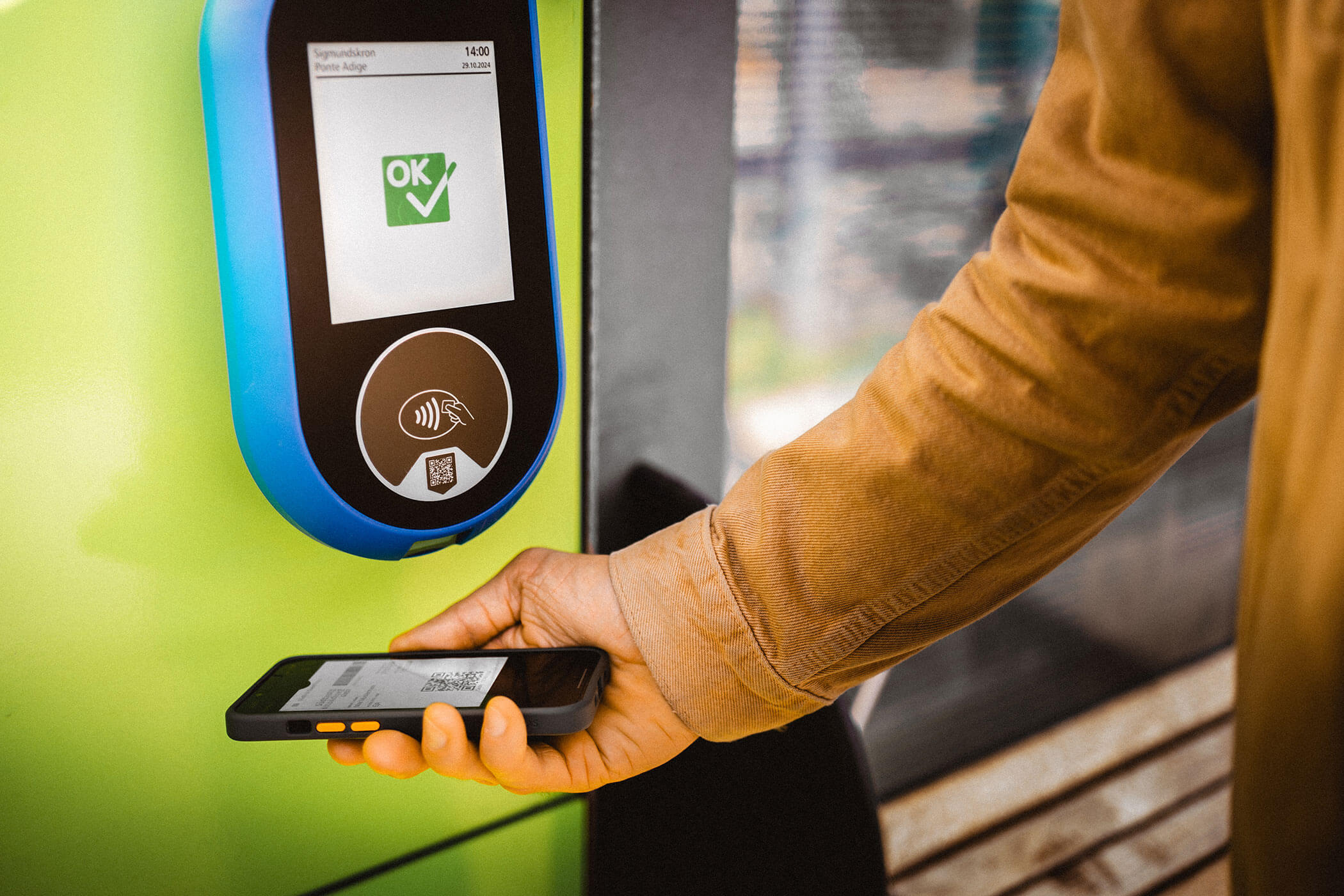A person scans a smartphone at a public transport ticket validator with a green OK check mark on display. - Hotel Innerhofer
