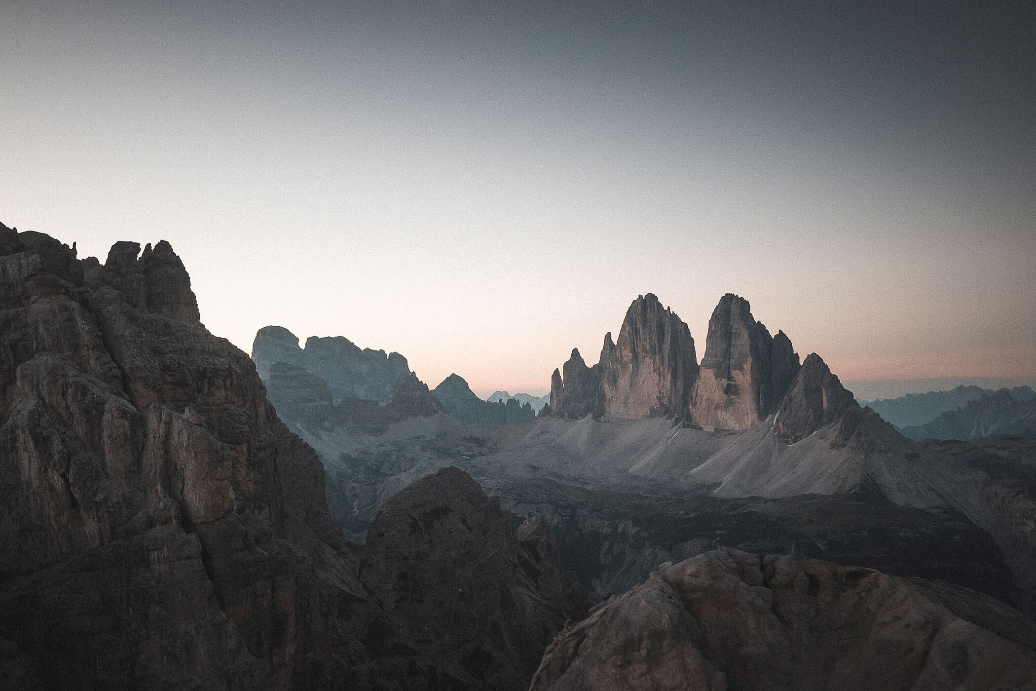 Jagged mountain peaks at sunrise with a soft, pastel sky in the background. - Hotel Innerhofer
