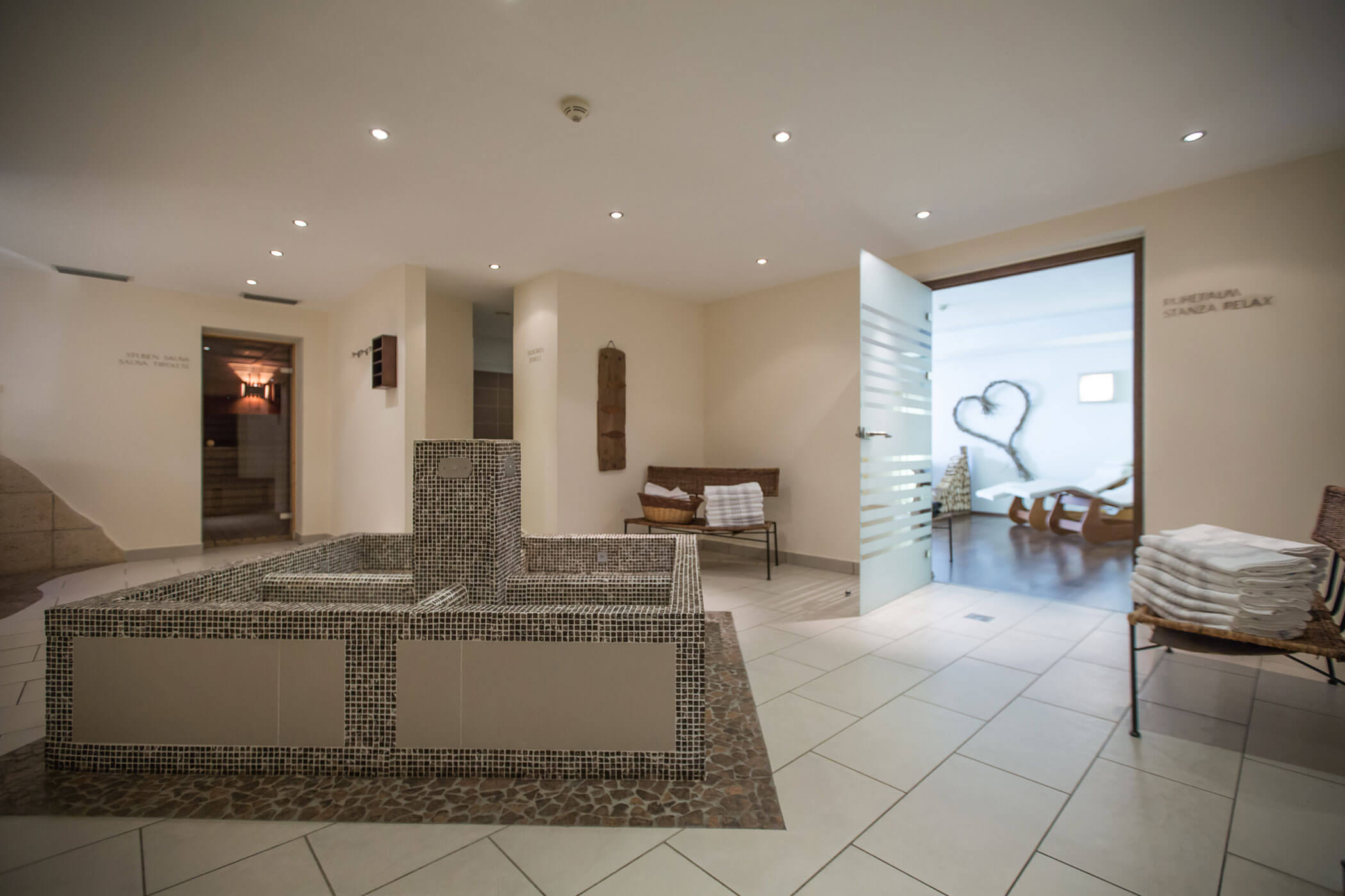Interno moderno della spa con fontana piastrellata, pareti bianche e una porta aperta che conduce alla sala relax. - Hotel Innerhofer